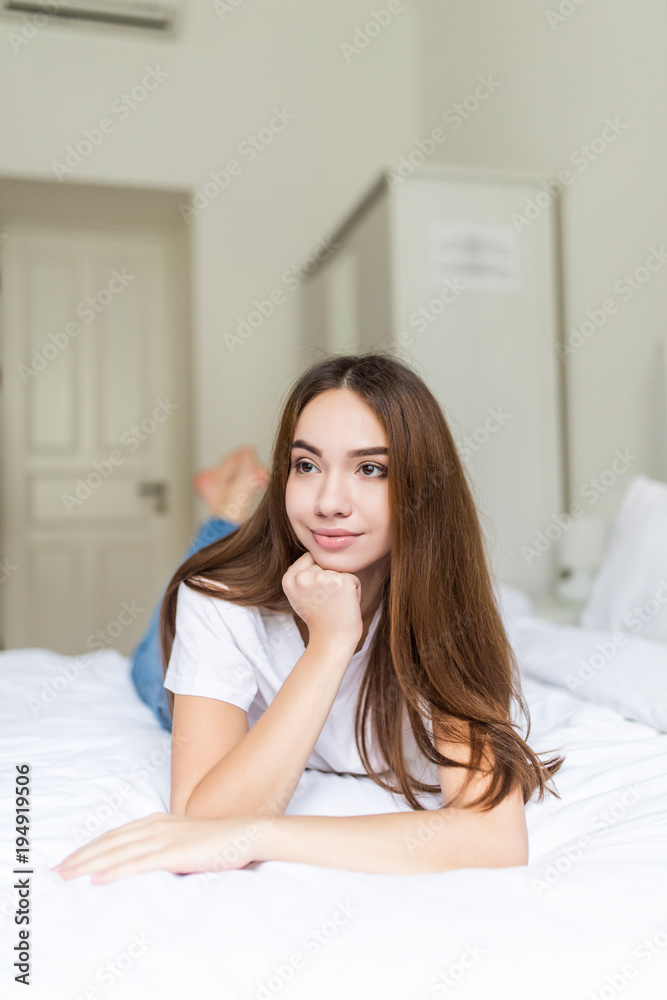 Beautiful young woman looking at camera while lying on the bed at home Beautiful young woman looking at camera while lying on the bed at home