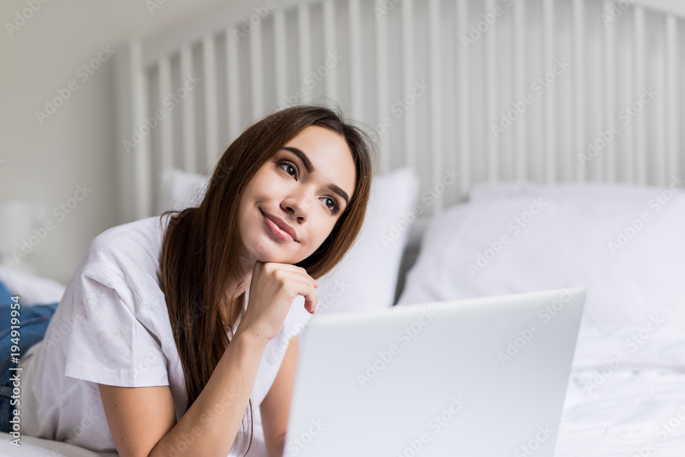Smiling woman with her legs raised slightly in front of her laptop lying on the bed. Smiling woman with her legs raised slightly in front of her laptop lying on the bed.