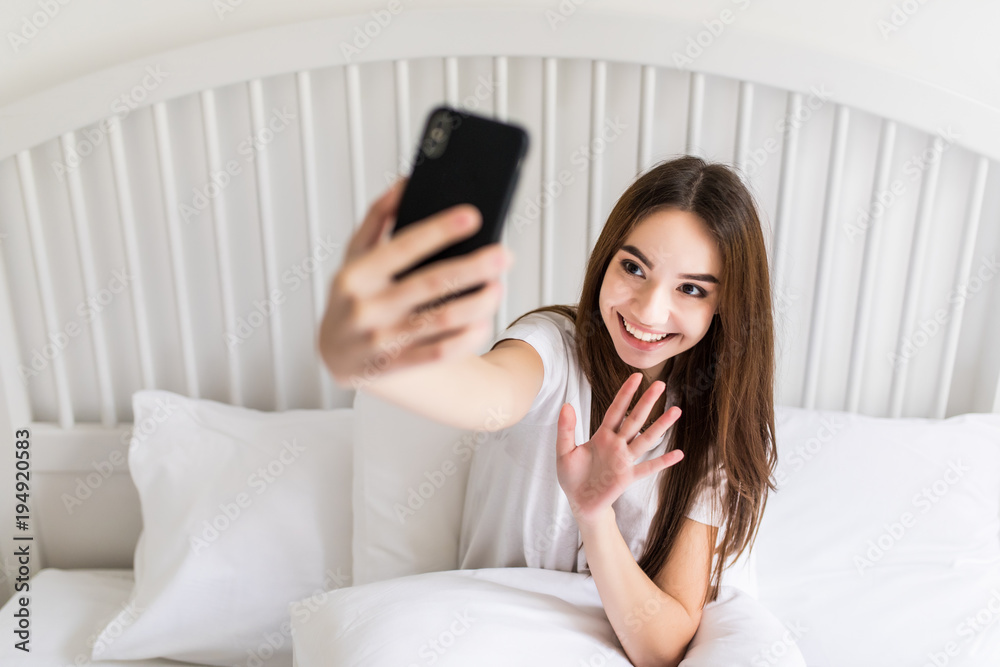 Beautiful girl making selfie in the bed. Beautiful girl making self on the bed at home. Selfie in the morning Beautiful girl making selfie in the bed. Beautiful girl making self on the bed at home. Selfie in the morning