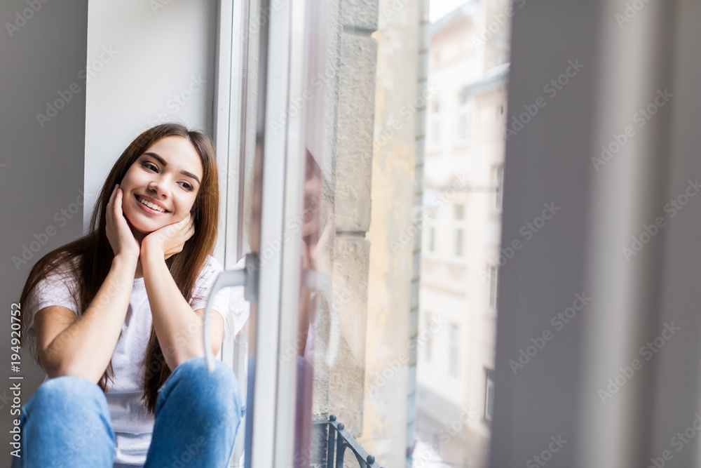 Beautiful smiling woman sitting on windowsill