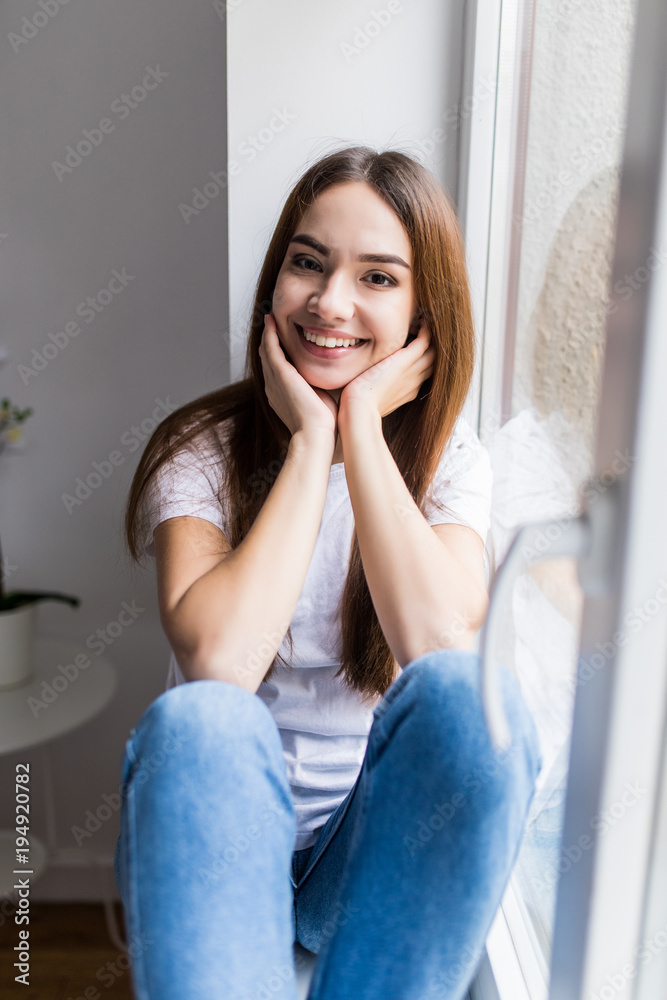 Beautiful smiling woman sitting on windowsill Beautiful smiling woman sitting on windowsill