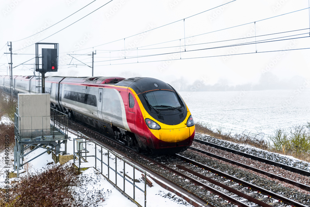 Fototapeta premium Cloudy foggy winter day view of Train on UK Railroad in England. Emma storm railway landscape.