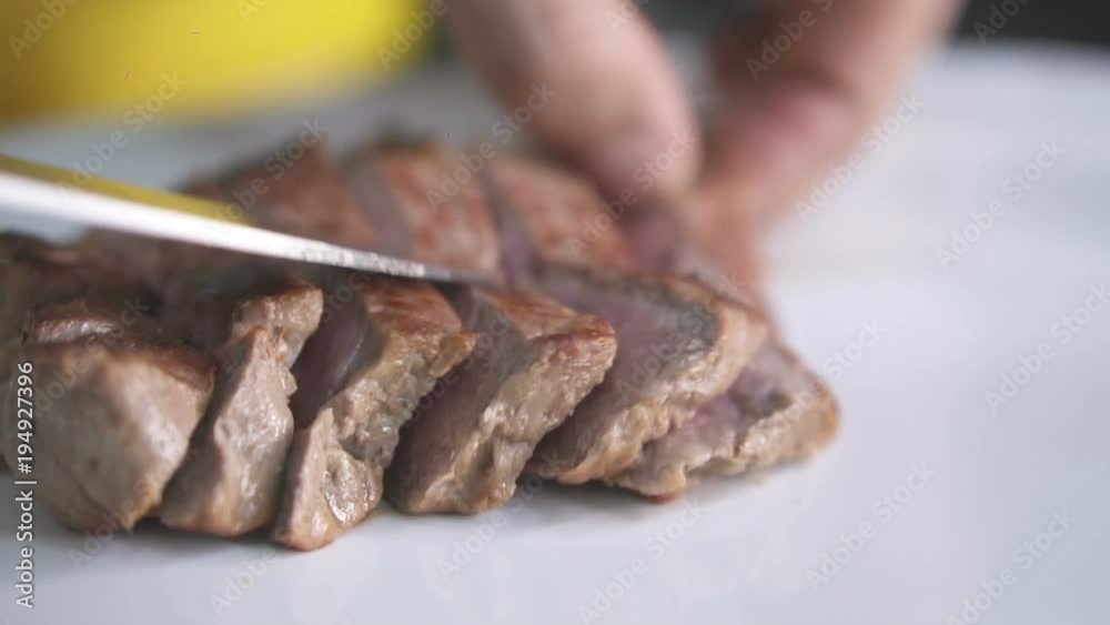 Closeup chef's hands putting sliced beef steak on clean plate. Dish preparation concept - video in slow motion Closeup chef's hands putting sliced beef steak on clean plate. Dish preparation concept - video in slow motion
