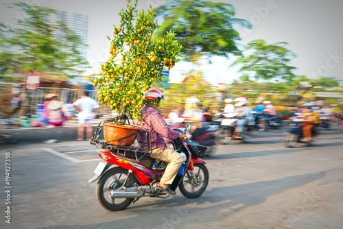 Ho Chi Minh City, Vietnam - February 13, 2018: A Vietnamese man is driving his motorcycle loaded with Fortunella japonica or Kumquat for decoration purpose lunar New Year in Ho Chi Minh City, Vietnam.