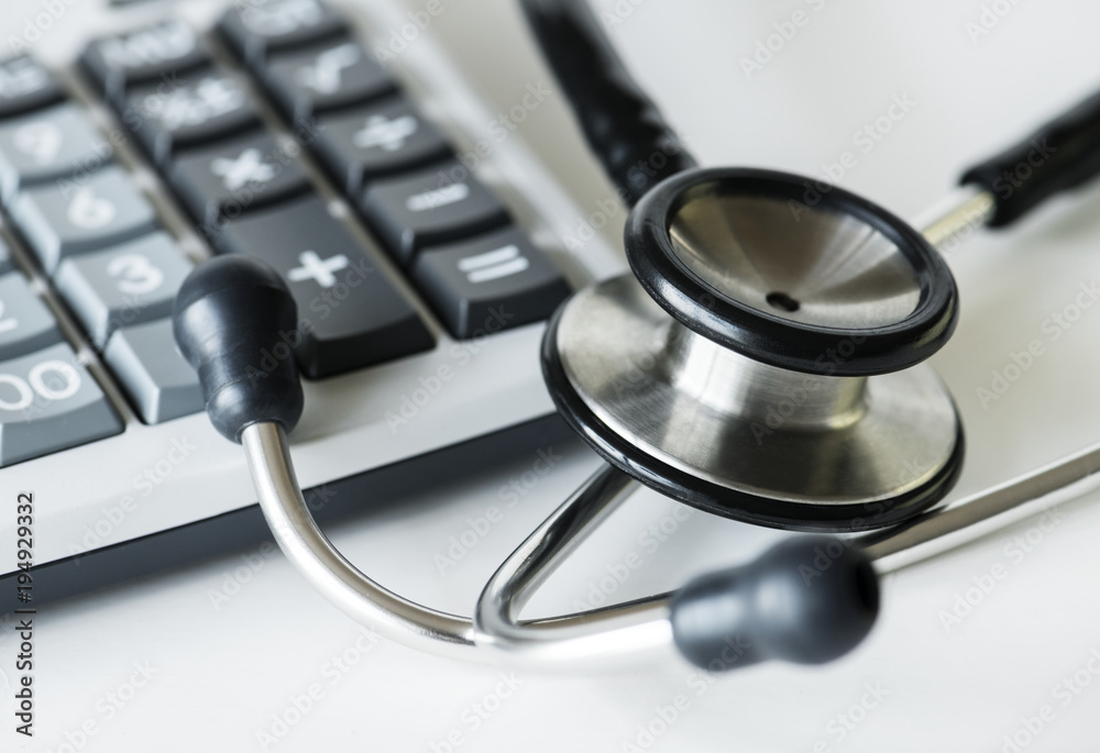 Closeup of a calculator and a stethoscope healthcare and expenses concept Closeup of a calculator and a stethoscope healthcare and expenses concept