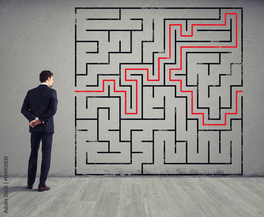 Businessman draws the solution of a labyrinth. Concept of problem solving