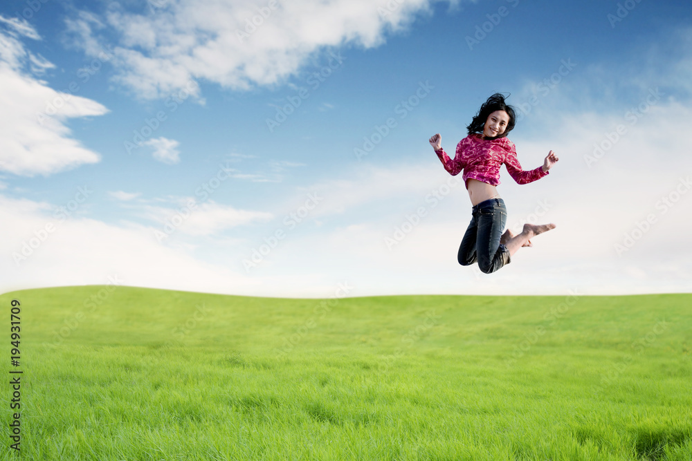Carefree Asian woman making a big jump on meadow. Carefree Asian woman making a big jump on meadow.