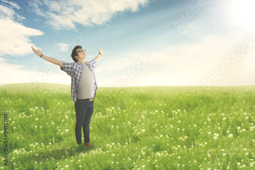 Happy man with arms wide open enjoying spring on blossom meadow. © Creativa Images
