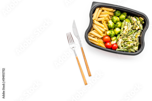 Healthy and hearty lunch for office worker. Vegetables Brussels sprout, cherry tomatoes, knock beans near pasta in plastic container on white background top view copy space