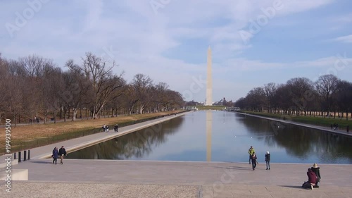 People Walking Near Water Source, Trees And Monument - Static photo