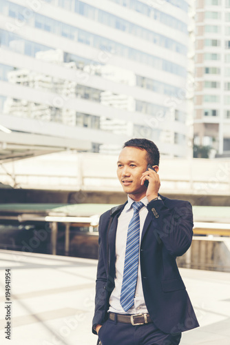 Asian handsome businessman using smart phone walking in the city.