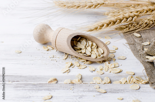 Fotografía Oat flakes in wooden scoop on dark  background