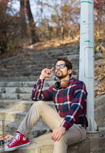 Portrait of a Male Sitting Holding Glasses and Looking Up