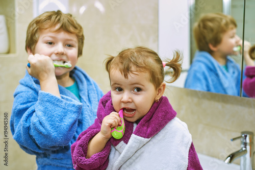 Obraz na płótnie Cute kids in bathrobes in the bathroom brushing their teeth w salonie