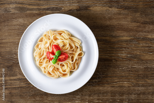 Plate with tagliatelle pasta on a wooden background.
