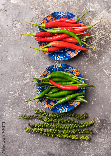 Different kinds of hot pepper red green black peas in bright dishes on a gray concrete background. photo