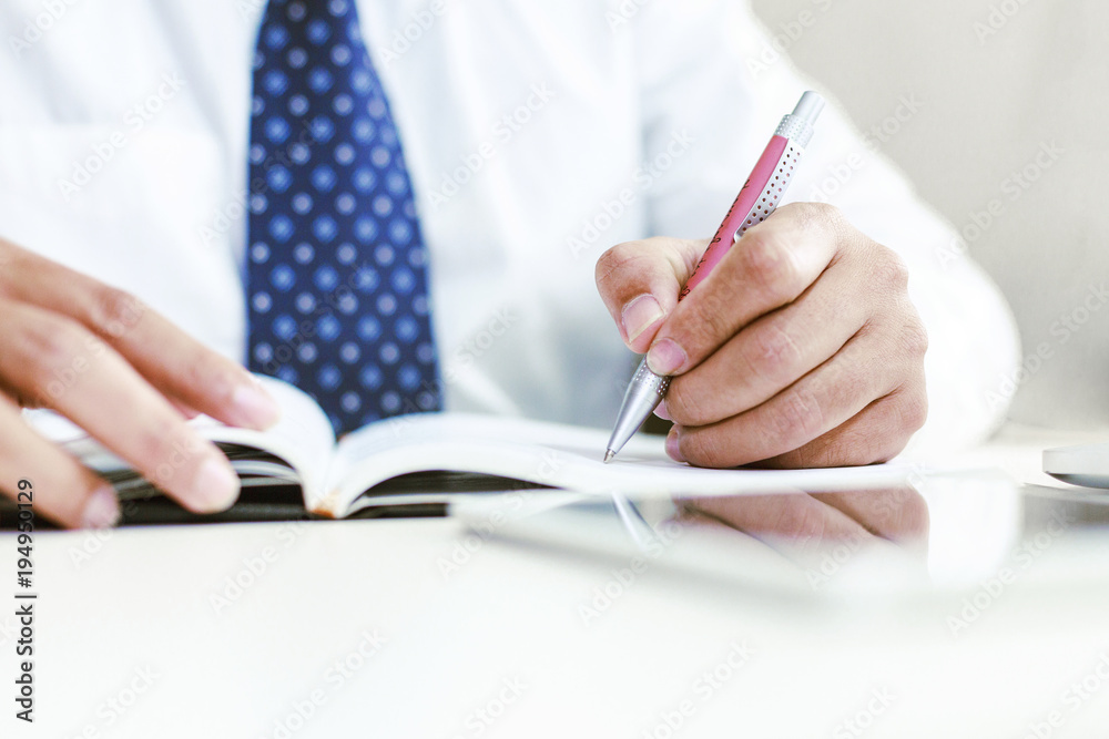 Businessman writing or drawing a note in a blank notebook Businessman writing or drawing a note in a blank notebook