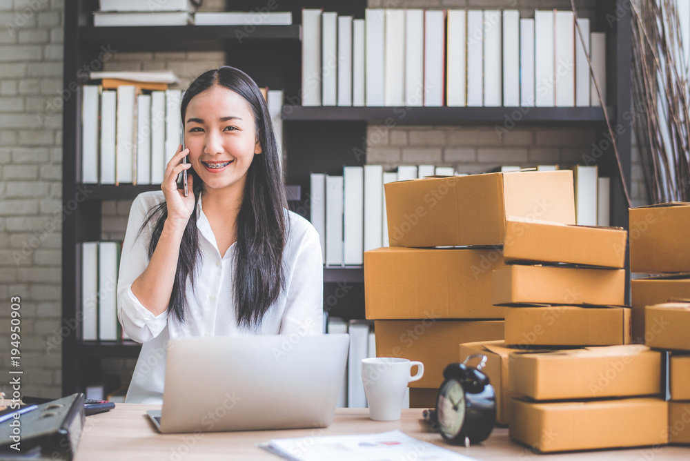 Happy young Asian woman answer phone from customer with her business online shopping at office. 
