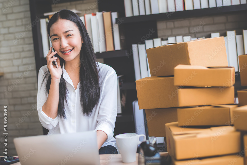 Happy young Asian woman answer phone from customer with her business online shopping at office. Happy young Asian woman answer phone from customer with her business online shopping at office.