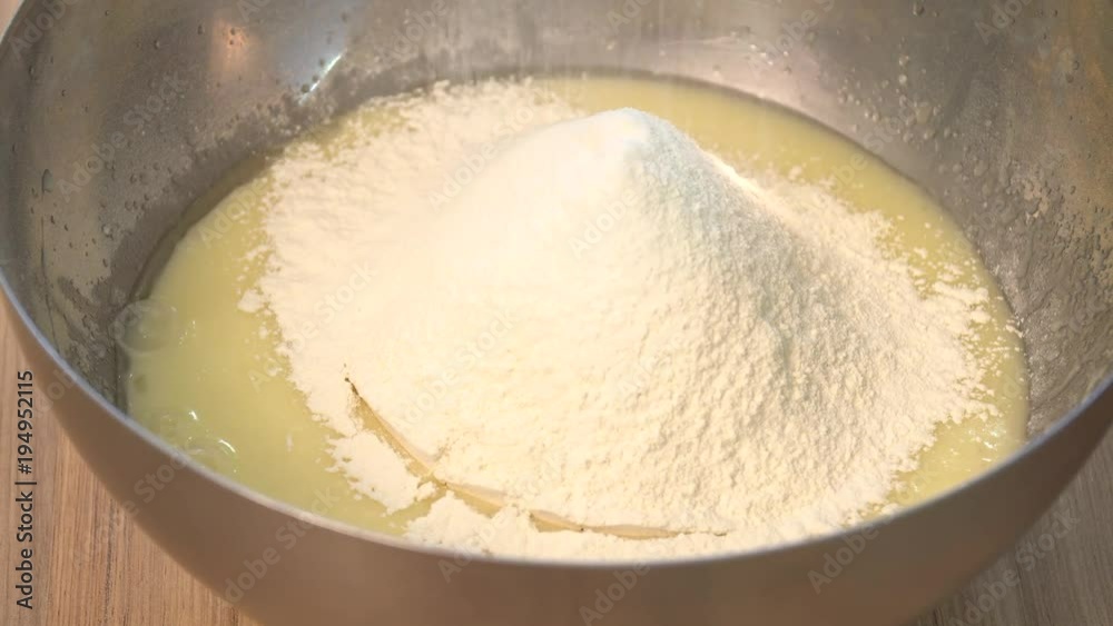 Sifting flour into bowl on table on wooden background Sifting flour into bowl on table on wooden background
