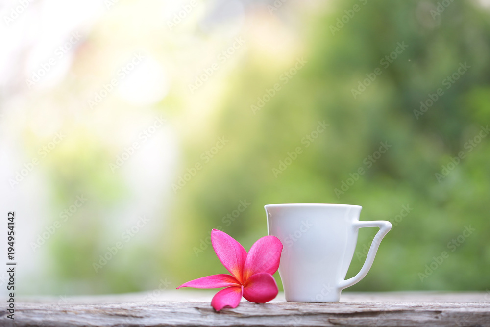 White cup with flower on wooden table