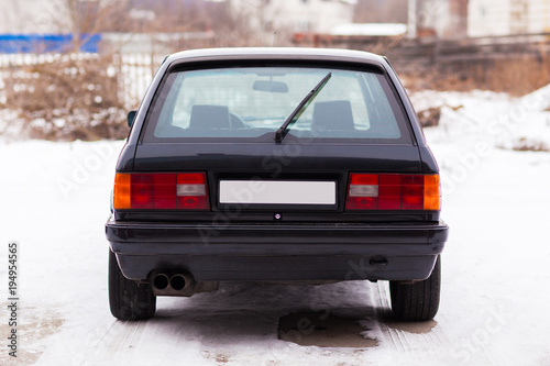 Old, black, German family car rear view in winter