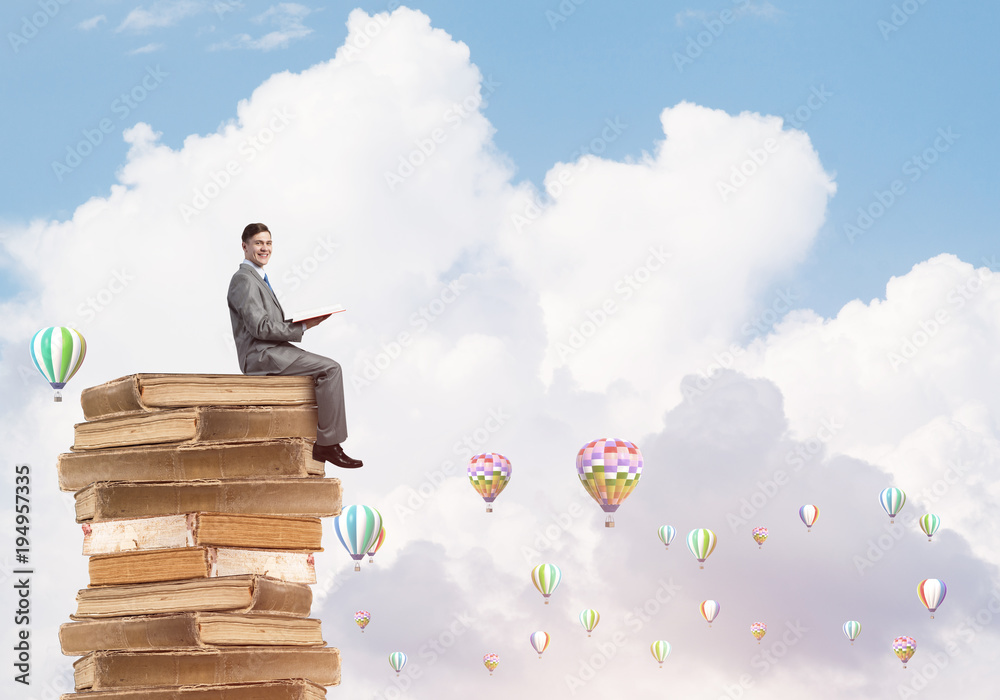 Man student reading book and aerostats flying around in air Man student reading book and aerostats flying around in air