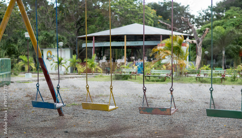 Fotografie Las Tunas, Cuba - September 4, 2017: Swingset with four different colored swings in an empty playground in the city