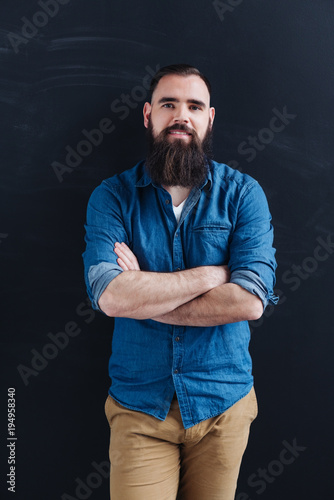 Self-assured relaxed bearded man in denim shirt