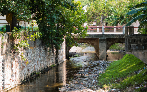 HOLGUIN, CUBA - AUGUST 31, 2017: Small bridge and canal in Cuba with visible litter everywhere.