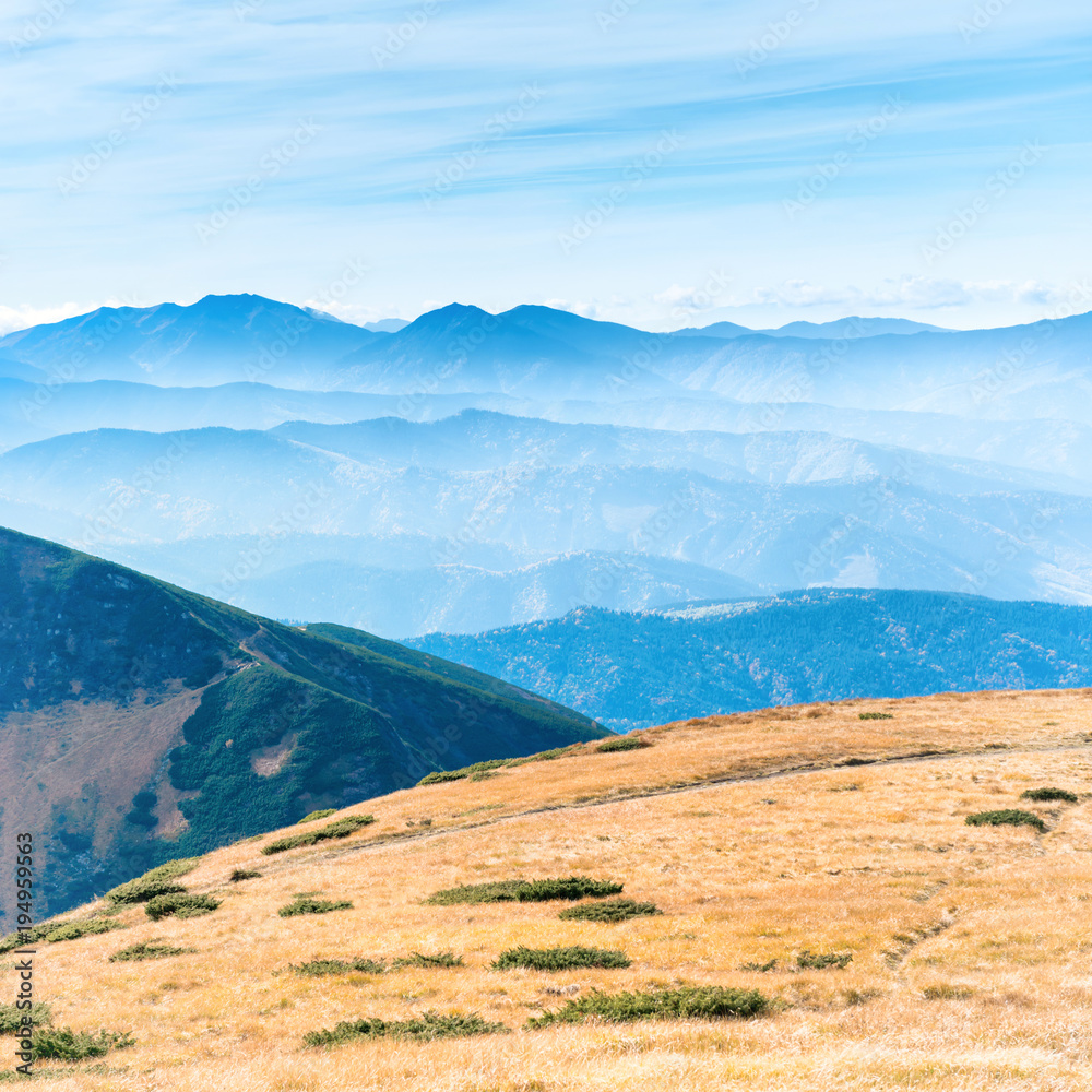 Mountains landscape with field of dry grass and blue sky