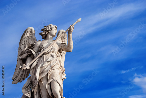Angel holding the Holy Lance of Longinus  with beautiful sky and copy space . A 17th century baroque masterpiece at the top of Sant Angelo Bridge in the center of Rome