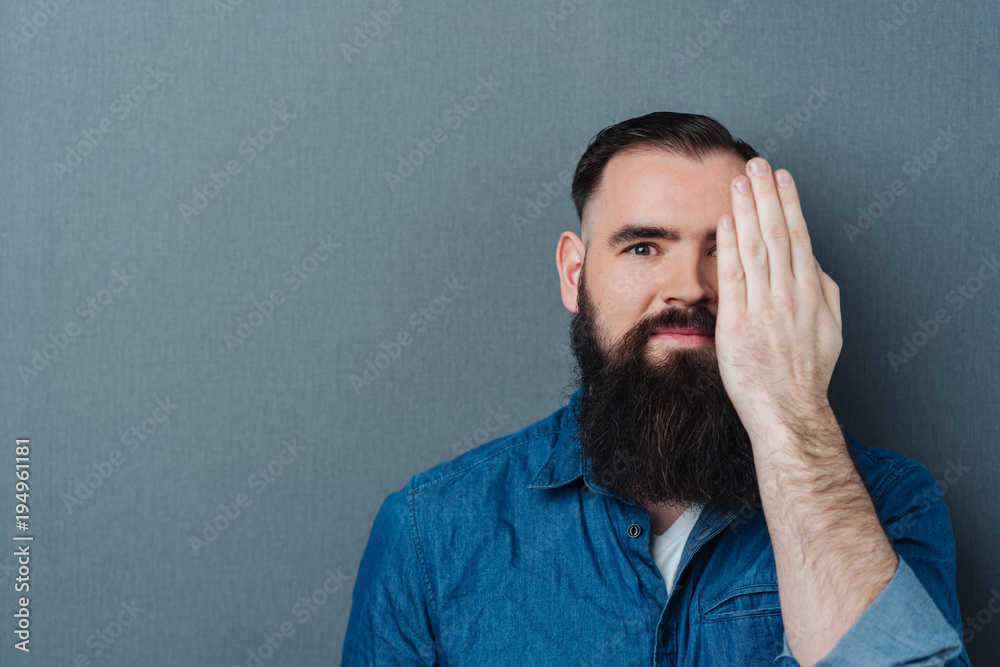 Bearded man covering one eye with his hand Bearded man covering one eye with his hand