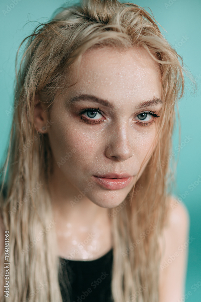 Young European attractive sexy fashion model with long blond natural hair, beautiful eyes, full lips, perfect skin is posing in jeans and shirt in studio for glamour vogue test photo shoot