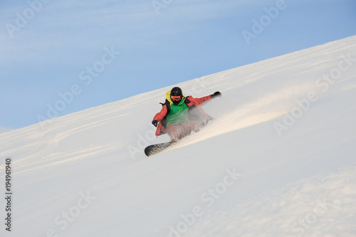 Active snowboarder riding down the snowy slope