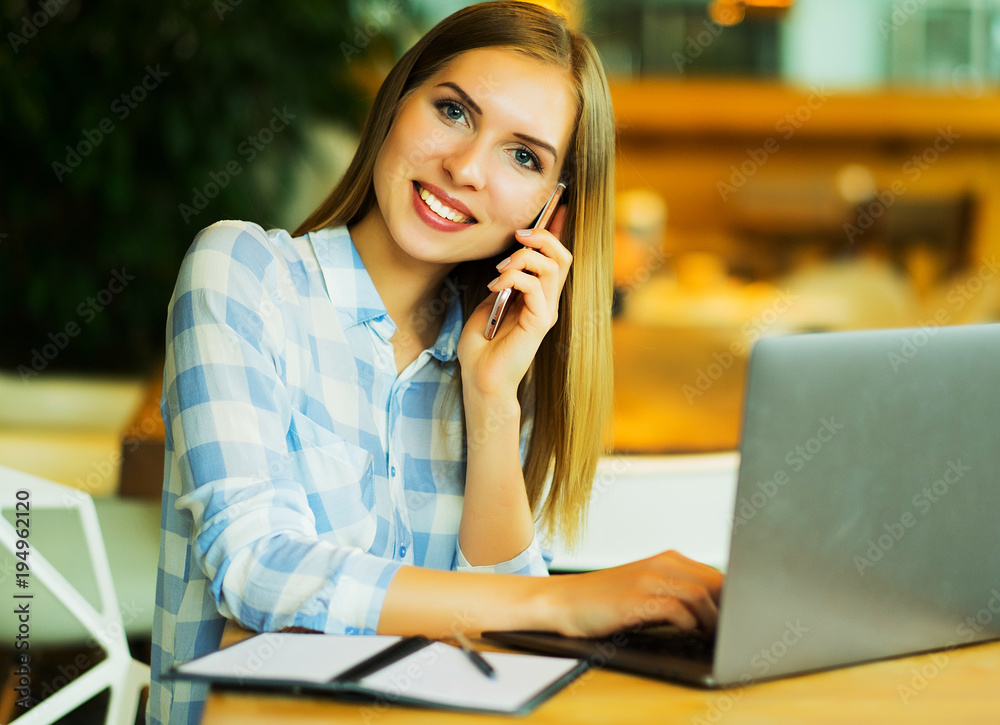 Business wooman using laptop at cafe. Young beautiful girl sitti Business wooman using laptop at cafe. Young beautiful girl sitti