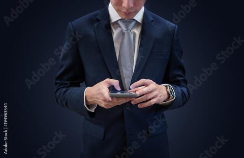 Businessman in dark blue suit using mobile smart phone, on blue background