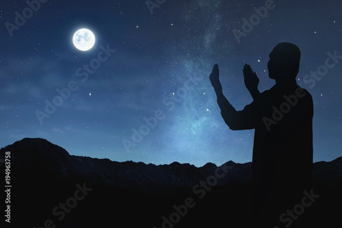 Silhouette of muslim man raising hand and praying to god