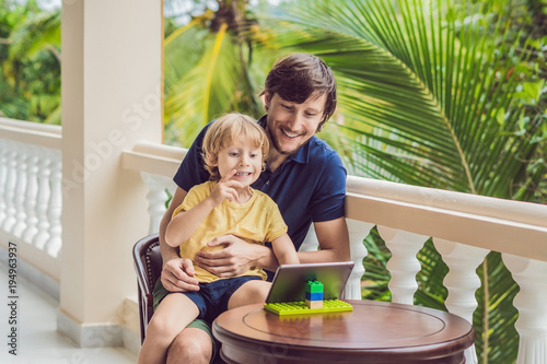 father and son in tropics talking with friends and family on video call using a tablet and wireless headphones photo