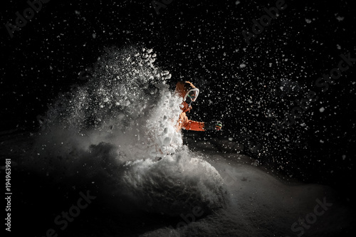 Freeride snowboarder jumping in snow at night
