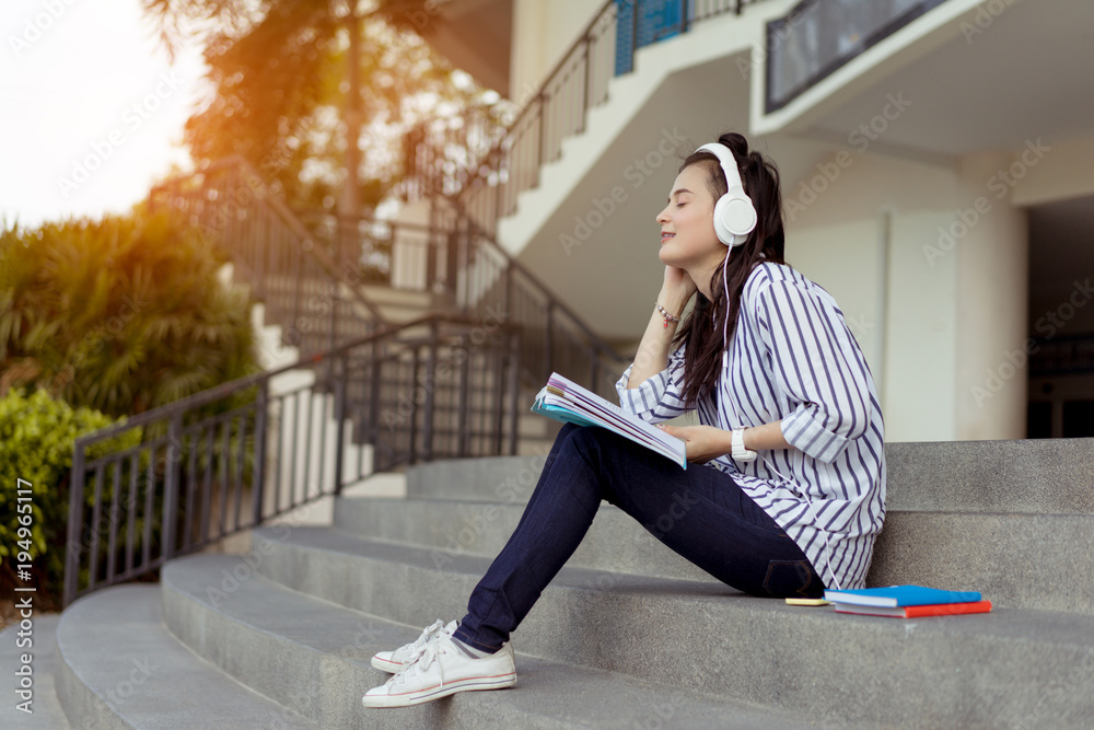 Young woman teenagers student listening music with headphone university college outdoor with school folder and relaxing having fun enjoy or study online concept