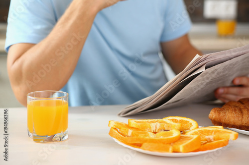 man in the kitchen eating a juice newspaper