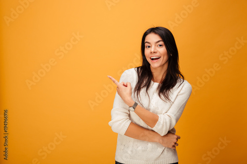 Cuadro en lienzo Portrait of a happy young woman pointing finger away