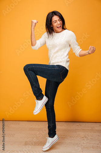 Full length portrait of a happy young woman celebrating