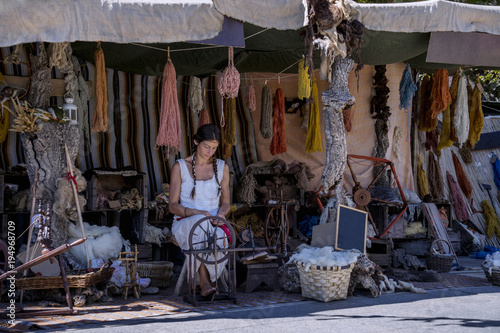 Woman using a spinning wheel, in a street market