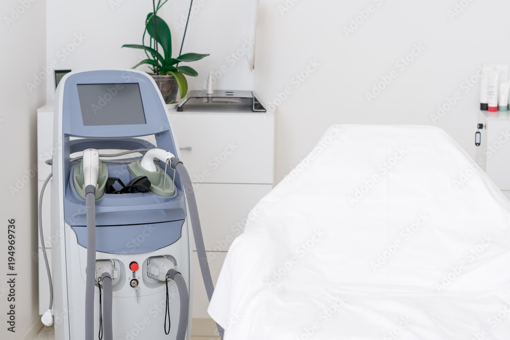 Fototapeta premium close up view of cosmetology apparatus and empty massage table in salon