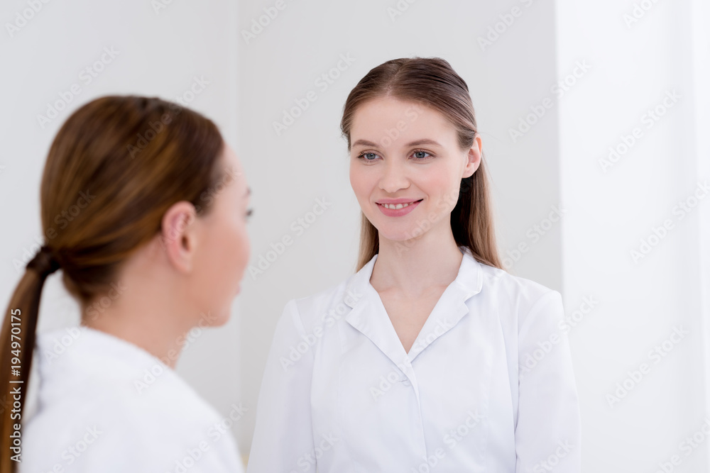selective focus of smiling cosmetologist and client in salon selective focus of smiling cosmetologist and client in salon