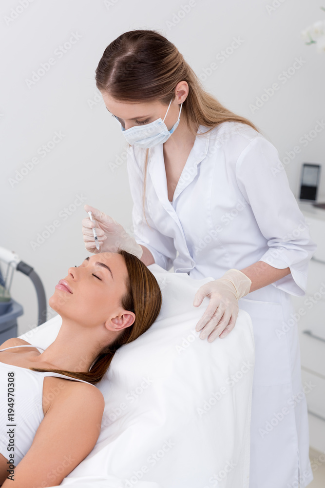 young woman getting beauty injection made by cosmetologist in salon