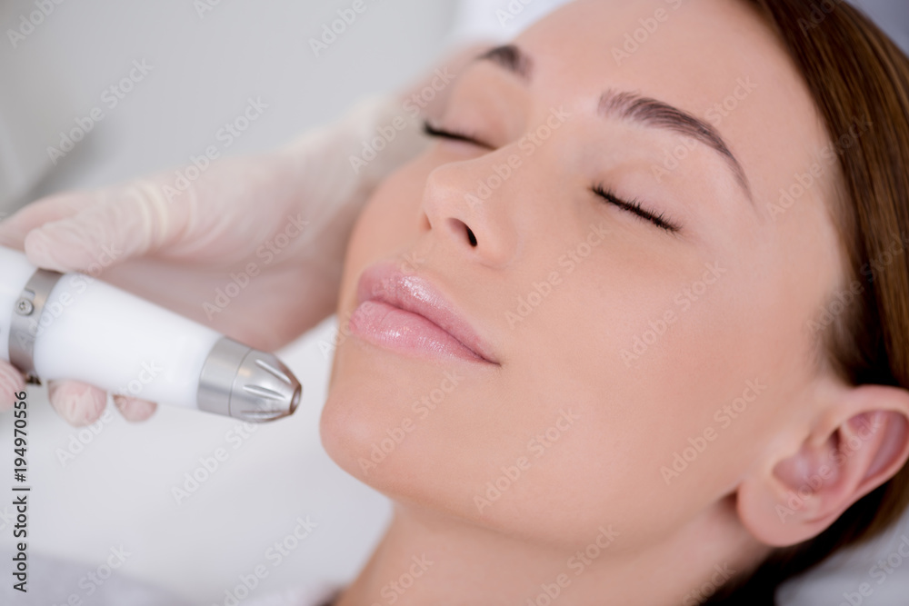 partial view of woman getting facial treatment in cosmetology salon partial view of woman getting facial treatment in cosmetology salon