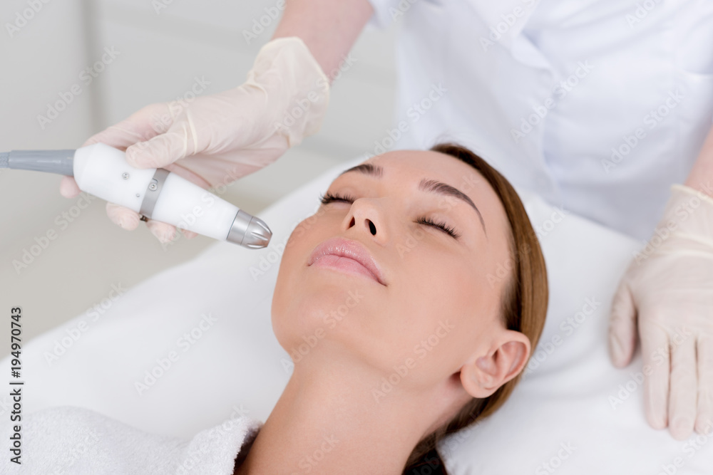 partial view of woman getting facial treatment in cosmetology salon partial view of woman getting facial treatment in cosmetology salon